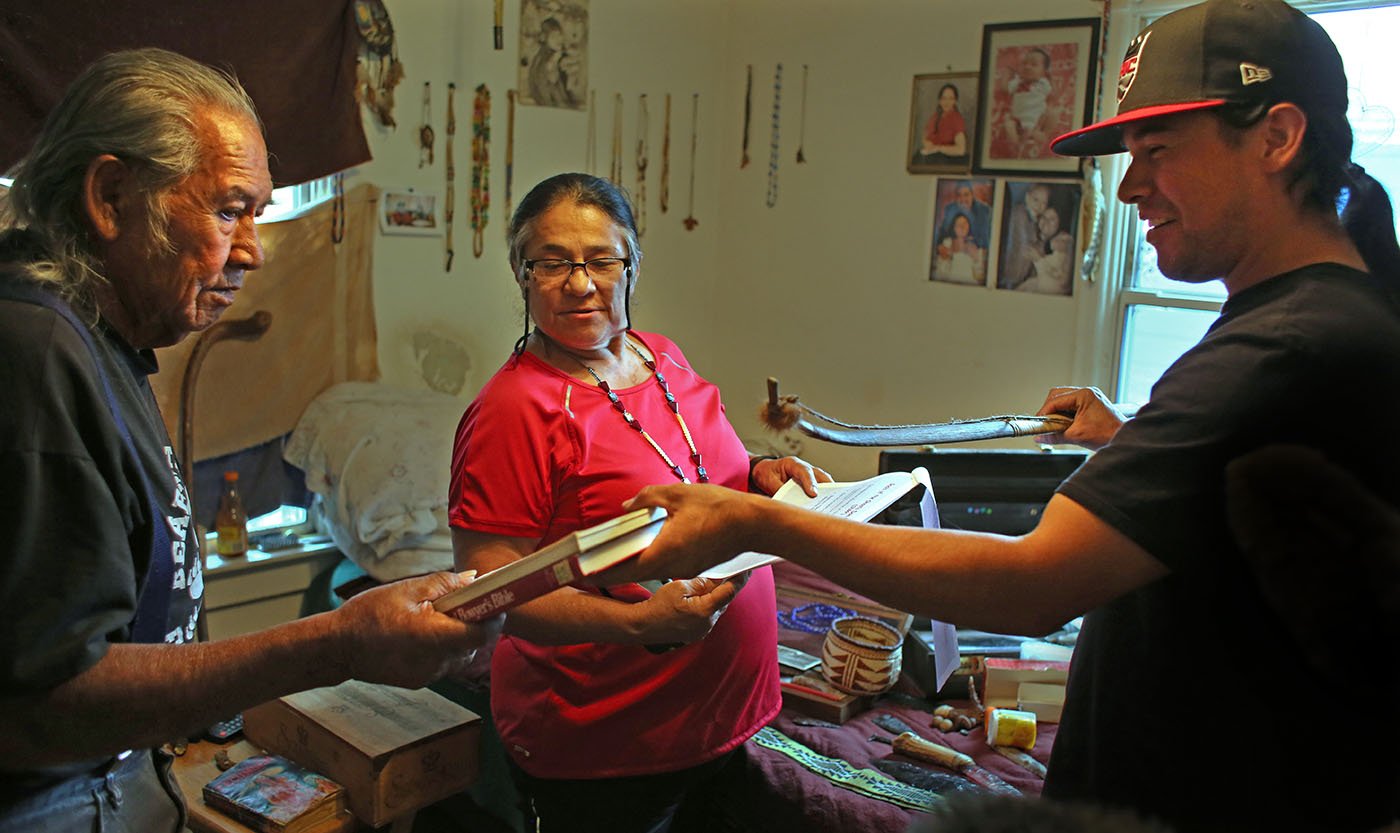 Hayfork, CA — Bob Burns lends a book about traditional indigenous craftsmanship to Arron Sisk. May 25, 2019. 
